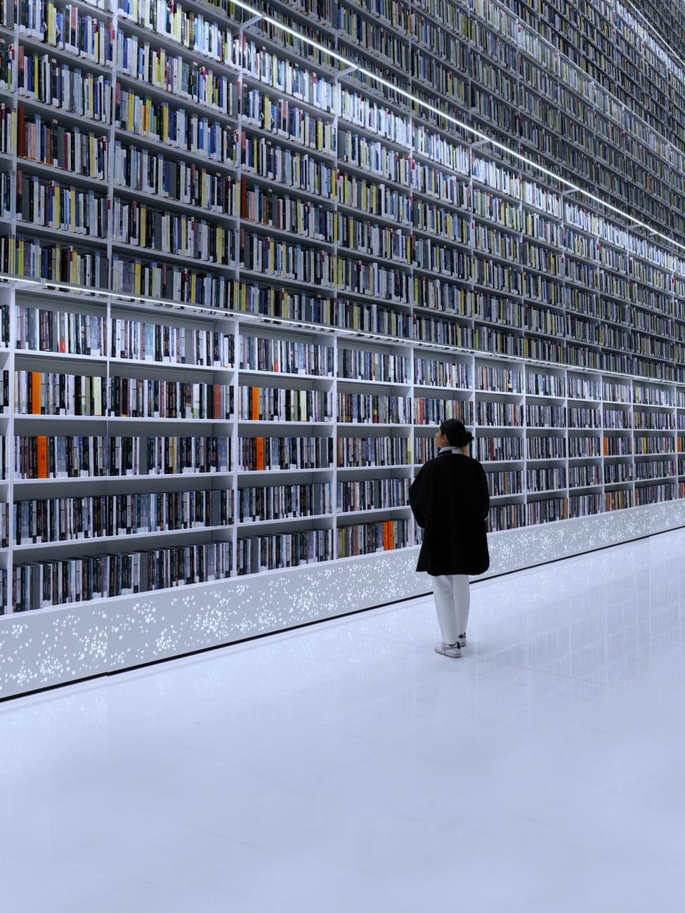 A person standing in a modern library with towering bookshelves in Dubai.